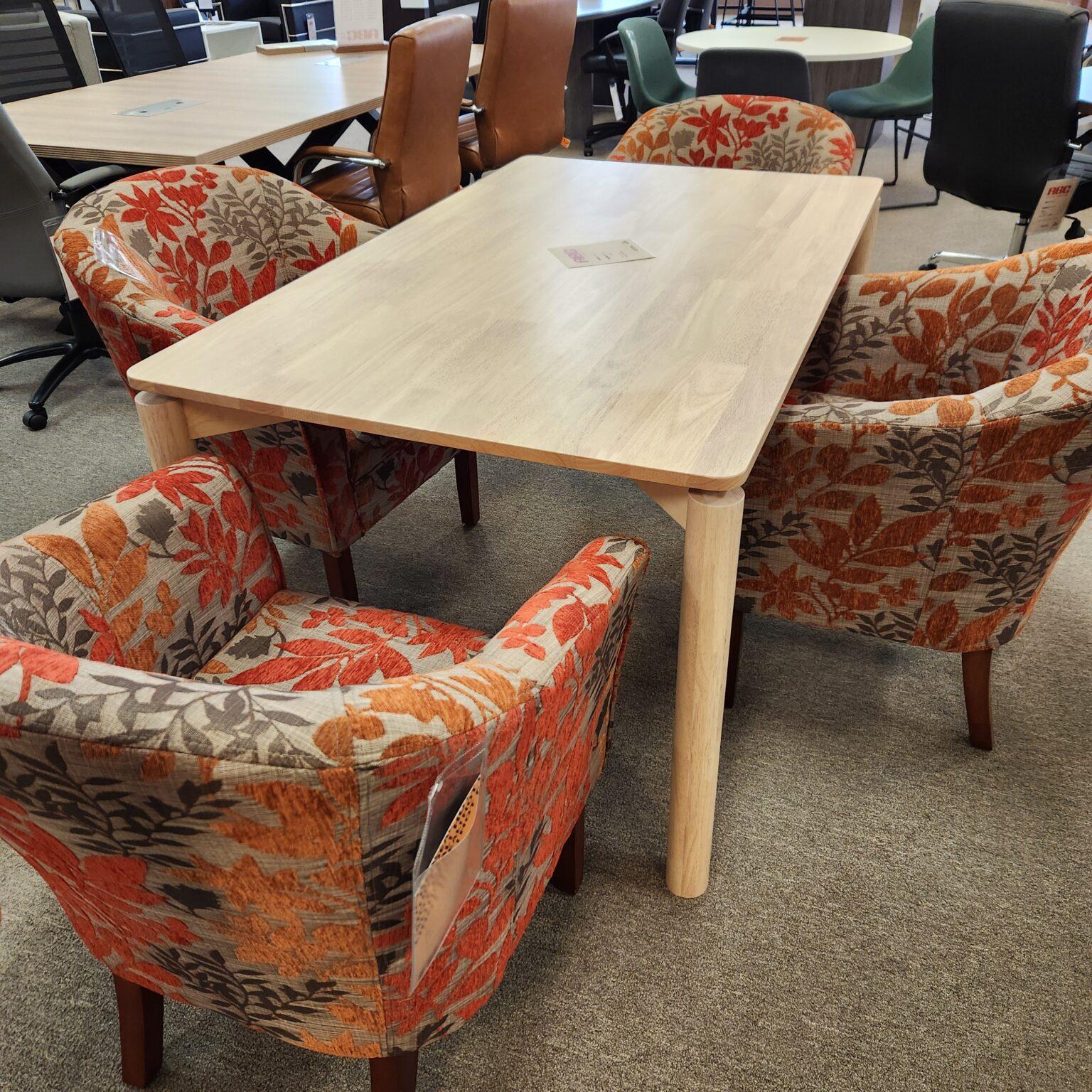 Image showing table and four chairs. Table is a light maple color and the upholstered chairs have a fall-themed leaf print