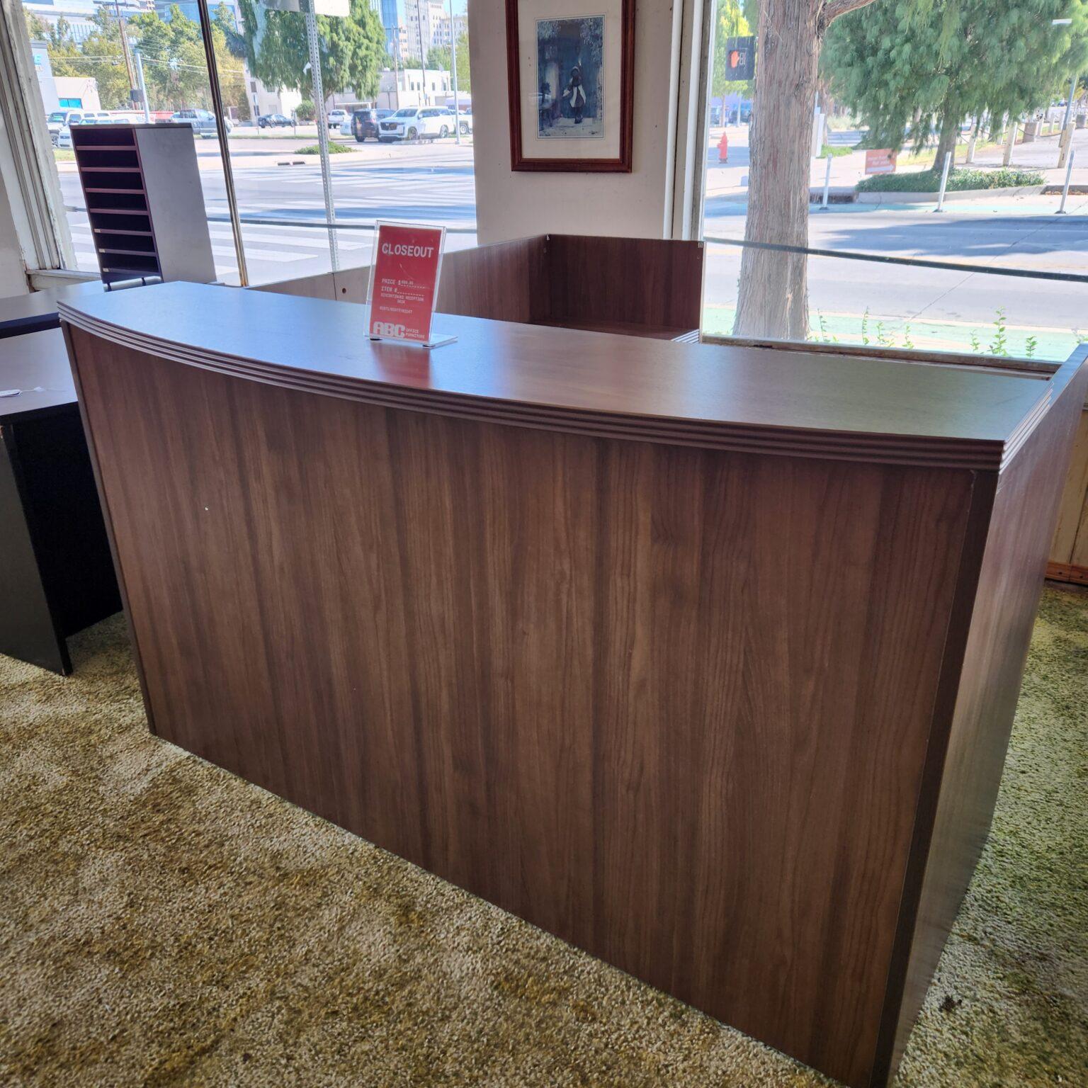 Reception desk with standing-height customer counter and L-shaped work space for employee.