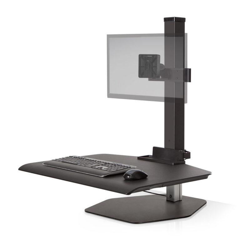 A black Winston Workstation sit-stand converter is shown against a white background, featuring a large work surface with a keyboard and mouse. A central black pillar supports an adjustable monitor mount with a semi-transparent panel representing a screen. The unit sits on a flat, hexagonal metal base and includes a small utility tray at the bottom of the support column.