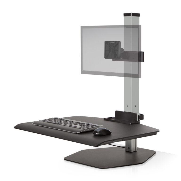 A gray Winston Workstation sit-stand converter is shown against a white background, featuring a large work surface with a keyboard and mouse. A central gray pillar supports an adjustable monitor mount with a semi-transparent panel representing a screen. The unit sits on a flat, hexagonal metal base and includes a small utility tray at the bottom of the support column.