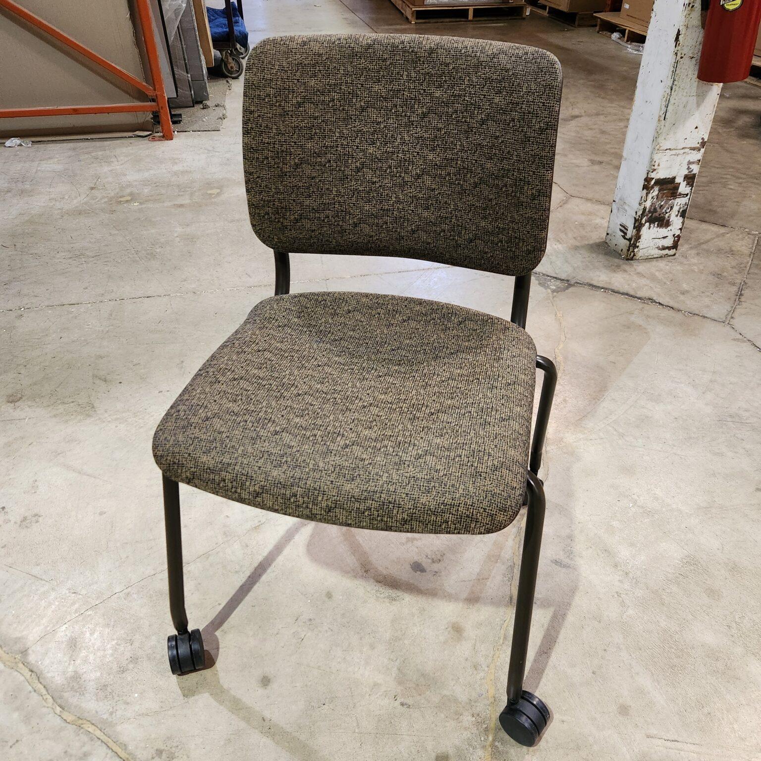 A front-view of a rolling stacking chair featuring olive and black textured fabric upholstery, a dark metal frame, and black casters on a concrete floor.