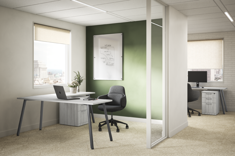 A dark gray textured Viva chair at a light wood L-shaped desk with a matching mobile pedestal in an office featuring a green accent wall and a whiteboard with handwritten diagrams.