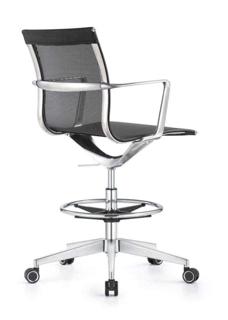 A Joan office stool from a rear three-quarter view, featuring black mesh upholstery, chrome armrests, a circular footrest, and a five-star chrome base with casters.